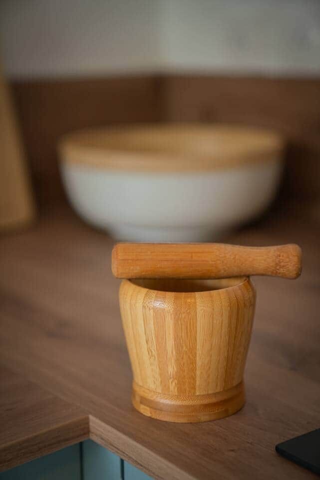 Un mortero de madera y un pilón sobre una encimera de cocina.