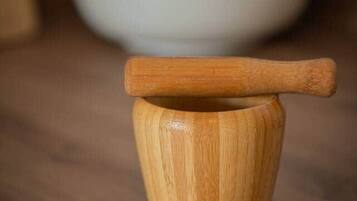 Un mortero de madera y un pilón sobre una encimera de cocina.