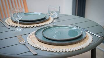 Une table dressée avec deux assiettes, deux verres à vin, une fourchette et un couteau.