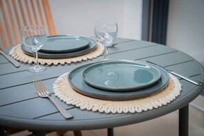 A table set with two plates, two wine glasses, a fork, and a knife.