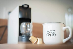 A white mug with "Mon Café" text, a coffee maker, and a glass.
