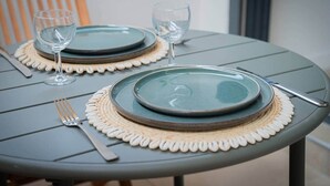Uma mesa posta com dois pratos, duas taças de vinho, um garfo e uma faca.
