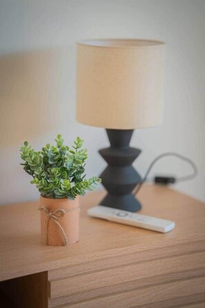 A wooden nightstand with a small potted plant and a lamp.