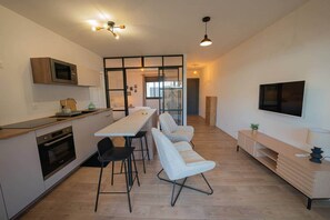 A modern kitchen with a dining area, a TV, and a seating area with a TV.