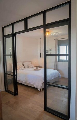A bedroom with a bed, a nightstand, and a window.