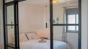 A bedroom with a bed, a nightstand, and a window. - Cosy T2 - La Verrière (La Possession)