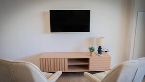 A modern room with a wooden desk, two chairs, a TV, a lamp, and a small plant. - Cosy T2 - La Verrière (La Possession)
