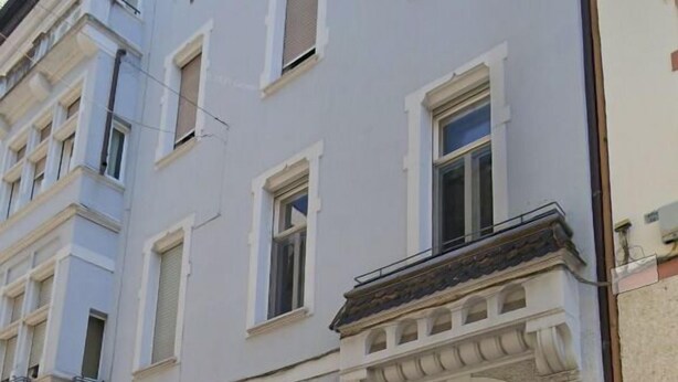A multi-story building with a classic architectural style, featuring a central entrance with a wooden door and decorative elements. - Talvera Dream (Bolzano)