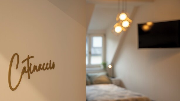 A bedroom with a bed, a hanging light fixture, and a wall with the name 'Cafinacci' written on it. - Talvera Dream (Bolzano)