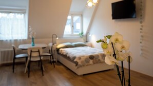 A bedroom with a bed, a desk, chairs, and a TV mounted on the wall. - Talvera Dream (Bolzano)