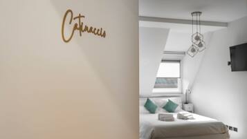 A modern bedroom with a bed, a nightstand, a wall-mounted light fixture, and a window with a view.