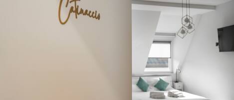 A modern bedroom with a bed, a nightstand, a wall-mounted light fixture, and a window with a view.