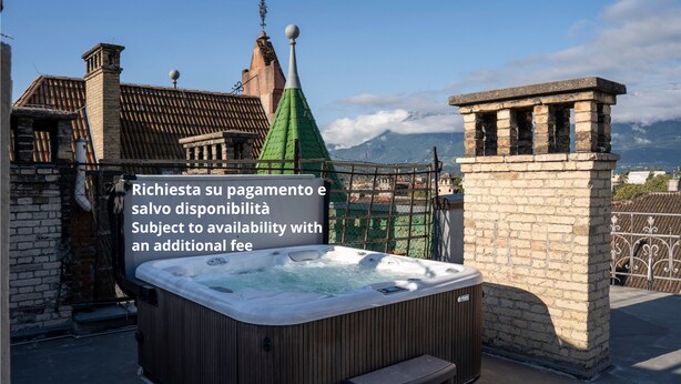 A hot tub on a rooftop with a view of mountains and traditional architecture in the background. - Talvera Dream (Bolzano)