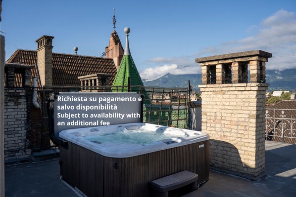 A hot tub on a rooftop with a view of mountains and traditional architecture in the background. - Talvera Dream (Bolzano)