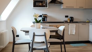 A modern kitchen with a dining area, featuring a white table, chairs, and a potted plant. - Talvera Dream (Bolzano)
