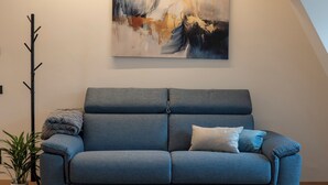 A modern living room with a grey sofa, a painting on the wall, and a potted plant. - Talvera Dream (Bolzano)