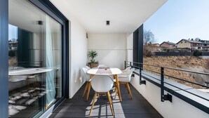 A balcony with a table and chairs, a potted plant, and a view of buildings. - Apartment 'Bei Stefanie' with Mountain View, Balcony and Wi-Fi (Bad Kötzting)