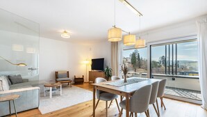 A modern living room with a dining area, large windows, and a view of the outdoors. - Apartment 'Bei Stefanie' with Mountain View, Balcony and Wi-Fi (Bad Kötzting)