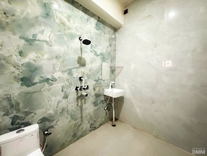 A bathroom with a marble wall, a shower, a sink, and a toilet. - Vimla Residency Hotel Near Prem Mandir (Vrindavan)