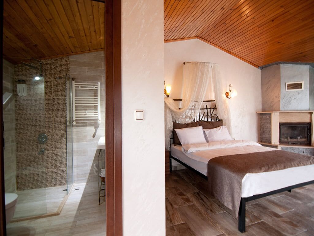 A bedroom with a bed, a glass shower enclosure, and a fireplace.