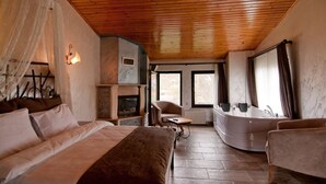 Un dormitorio con techo de madera, una cama, un sofá, una mesa y una chimenea empotrada.