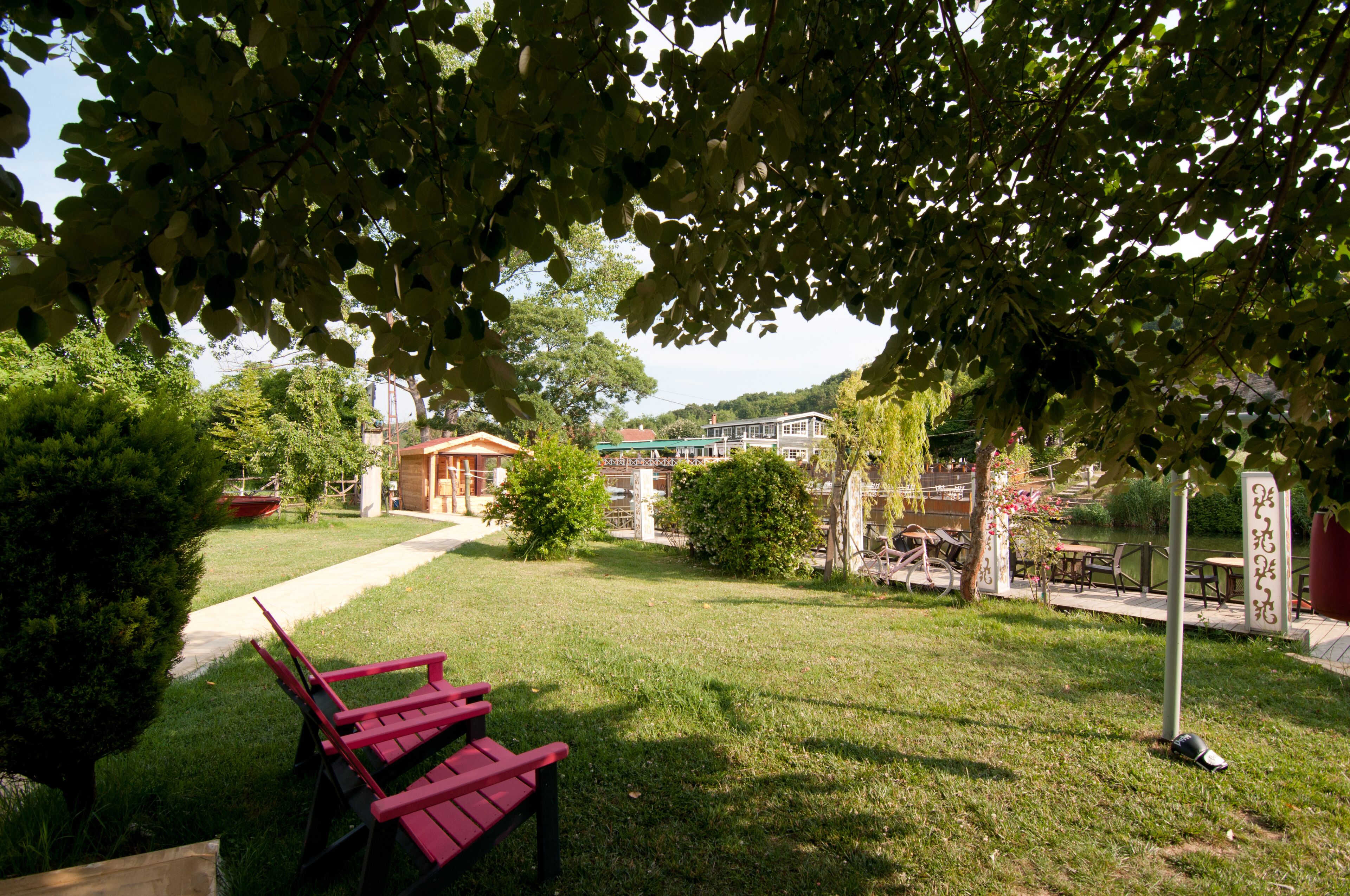 A grassy outdoor area with a red bench, a pathway, and a building in the background.