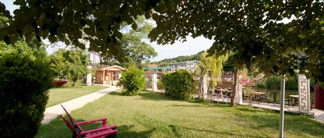 A grassy outdoor area with a red bench, a pathway, and a building in the background.