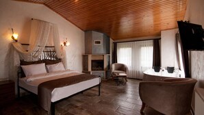 Un dormitorio con techo de madera, una cama, una silla, una mesita y una chimenea.