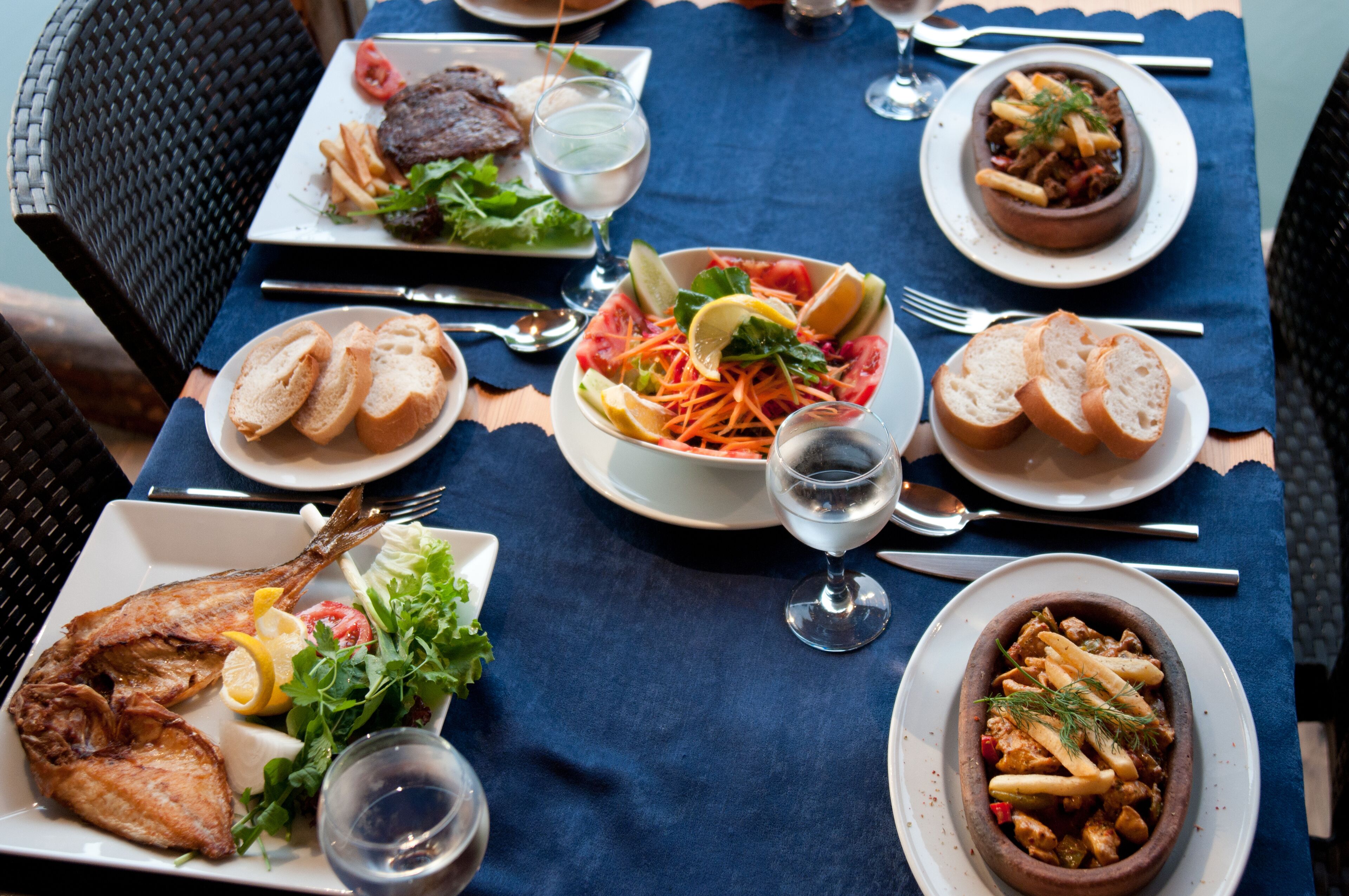 A table set with various dishes including fish, salad, and bread, with a blue tablecloth.