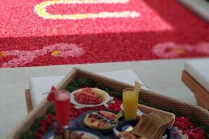 Une table sur laquelle se trouve un panier contenant de la nourriture et des boissons, le tout posé sur un meuble recouvert d’un tapis rouge.