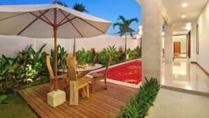 Une terrasse extérieure avec une plateforme en bois, une table ronde et un grand parasol.