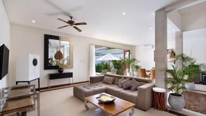 Un salon moderne avec un canapé d’angle, une table basse et un ventilateur de plafond.