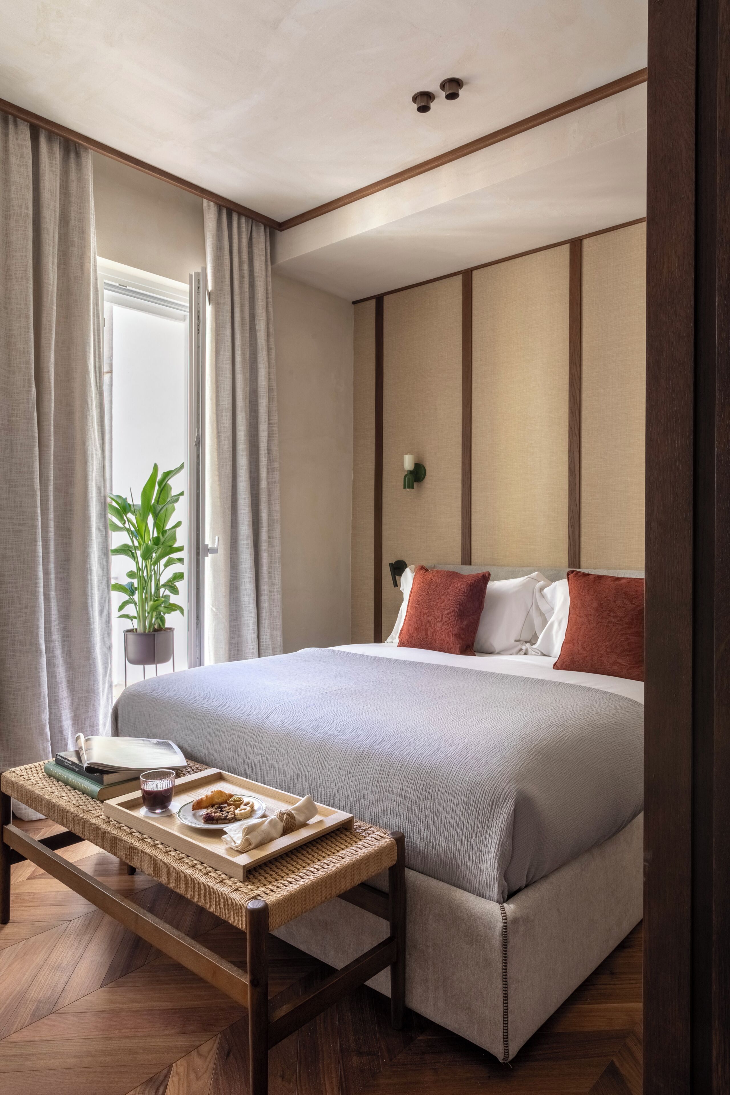 Une chambre d’hôtel bien rangée, avec un lit, une table de chevet et une plante en pot.