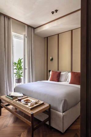 Habitació d'hotel acuradament ordenada, amb llit, taula de nit i una planta en test.
