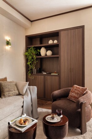 Un salon comprenant un canapé, un fauteuil, une table basse et un meuble en bois doté d’étagères.