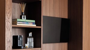 Una habitación moderna con un escritorio de madera, un televisor de pantalla plana, una estantería y una silla.