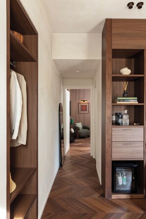Un pasillo con estanterías de madera, un refrigerador y un sofá al fondo.