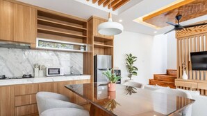 A modern kitchen with wooden cabinets, a glass dining table, and a built-in oven. - Orivista NEW! Luxe Private Pool Villa w Rooftop (Mengwi)