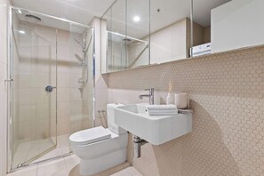 Une salle de bain moderne avec une douche à parois de verre, un lavabo blanc et des toilettes.