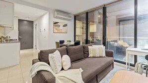 Een moderne woonkamer met een bank, een eethoek en een groot raam.