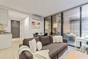 Un salon moderne avec un canapé, un coin repas et une grande fenêtre.