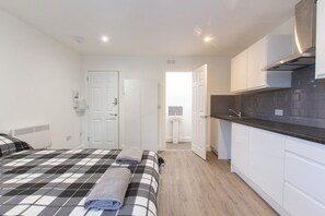 A bedroom with a checkered bedspread, a neatly made bed, and a bathroom visible through an open door. - Bridge Road - Room 2b (Southampton)