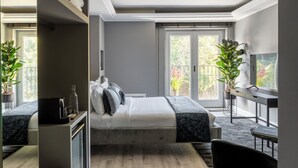A modern bedroom with a bed, bedside table, and a large window with a view of greenery. - Naman Hotellerie - Condotti (Rome)