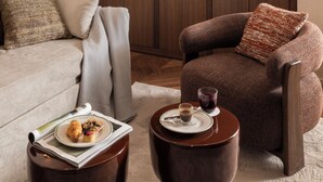 A living room with a sofa, armchair, coffee table, and a wooden cabinet with shelves. - Naman Hotellerie - Condotti (Rome)