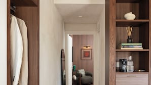 A hallway with wooden shelving, a small refrigerator, and a sofa in the background. - Naman Hotellerie - Condotti (Rome)