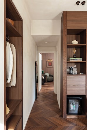 A hallway with wooden shelving, a small refrigerator, and a sofa in the background. - Naman Hotellerie - Condotti (Rome)