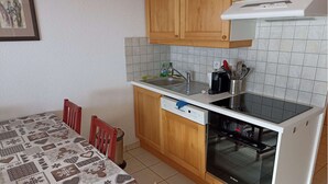 Een compacte keuken met houten kastjes, een Bosch vaatwasser en een betegelde spatwand.