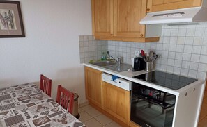 Une cuisine compacte avec des meubles en bois, un lave-vaisselle Bosch et un pare-feu en carrelage.