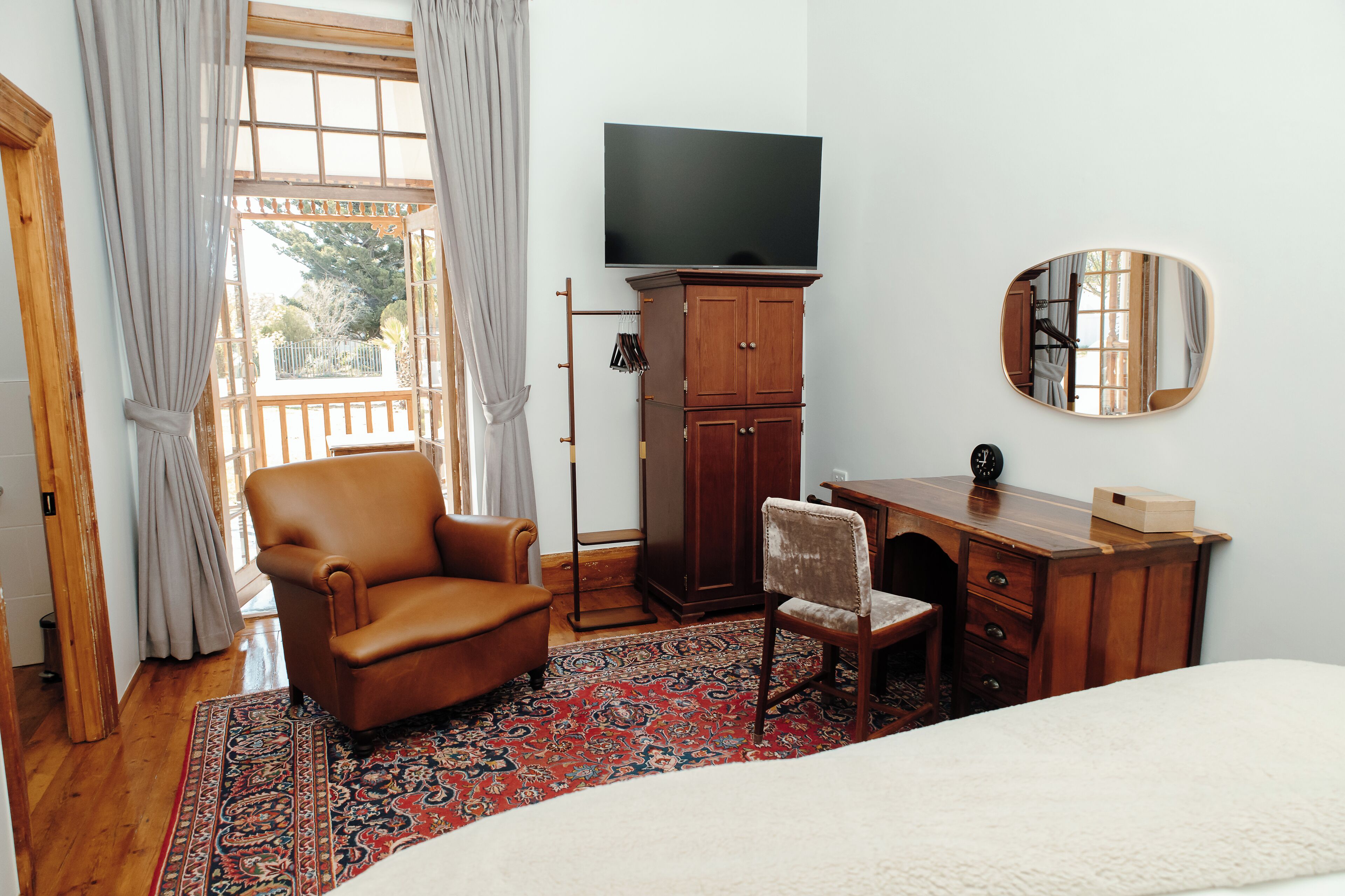 Een slaapkamer met een groot bed, een houten bureau, een stoel, een televisie en een kledingkast.