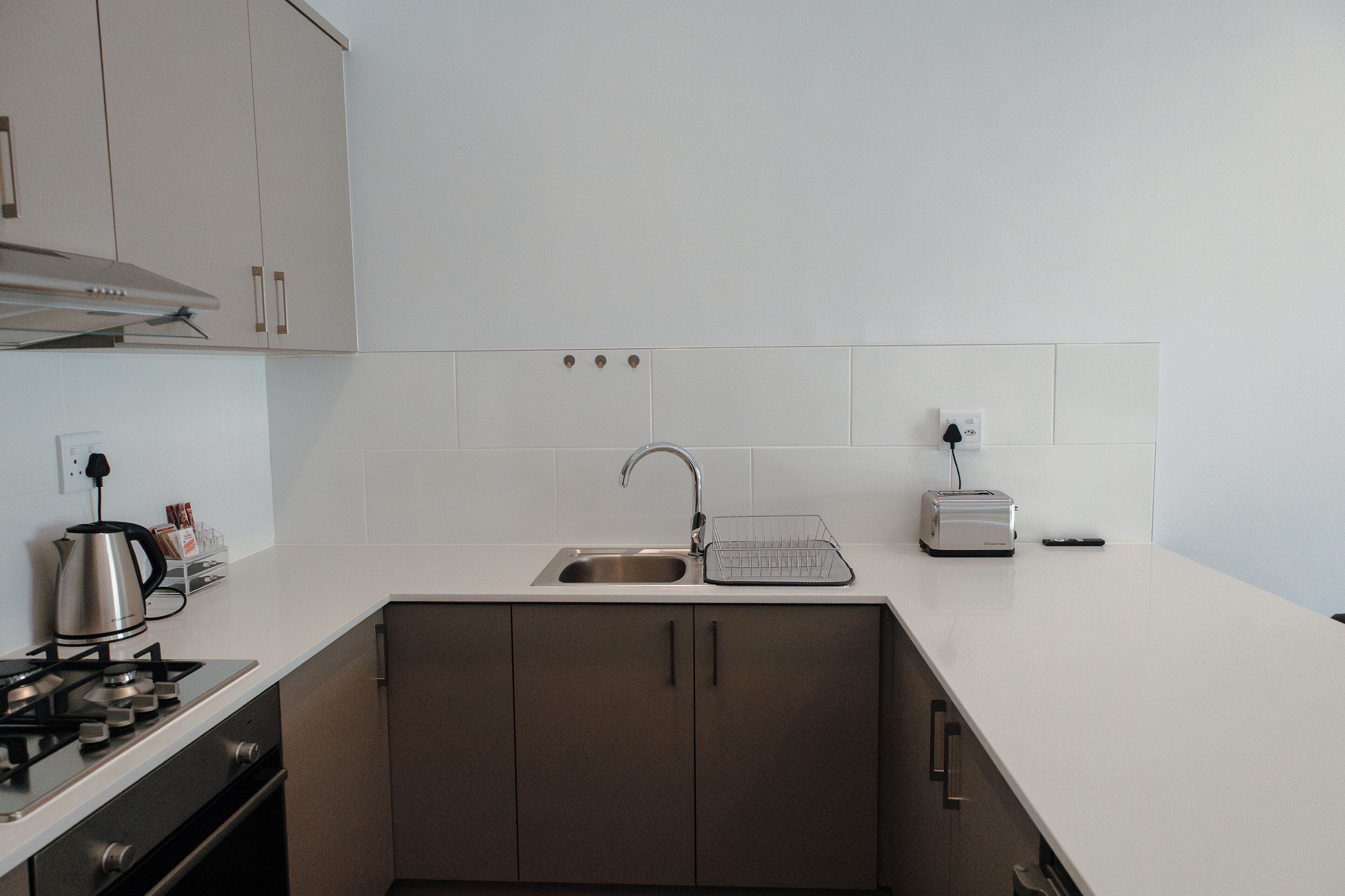 Una cocina moderna con un lavamanos de acero inoxidable, un tostador y una tetera sobre la encimera.